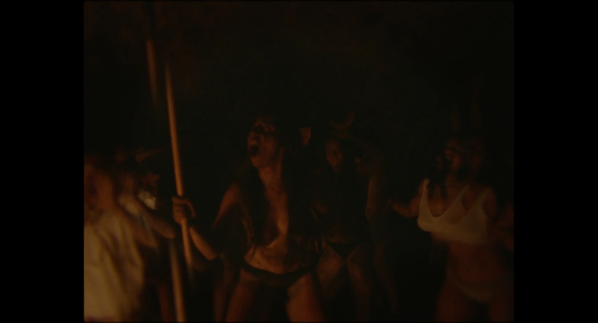 People in a dark space, their faces and bodies illuminated by warm firelight