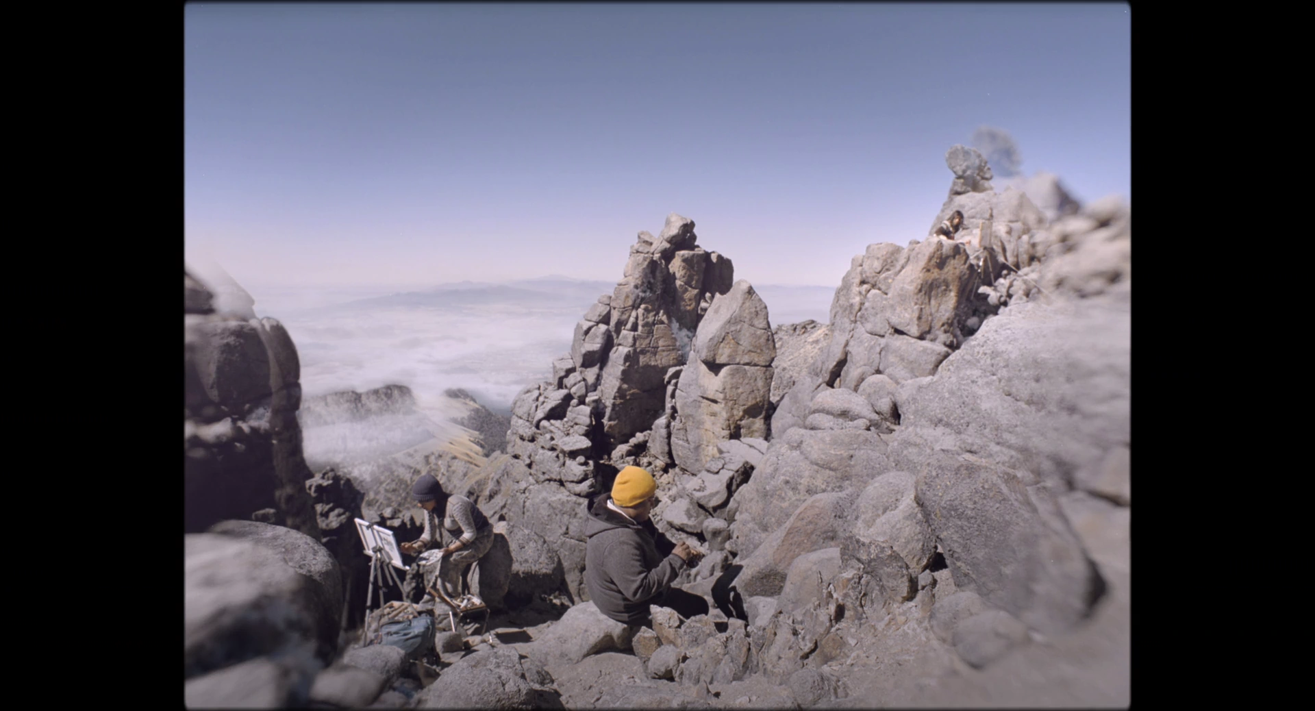 People among tall rock formations beneath a clear sky in strong daylight