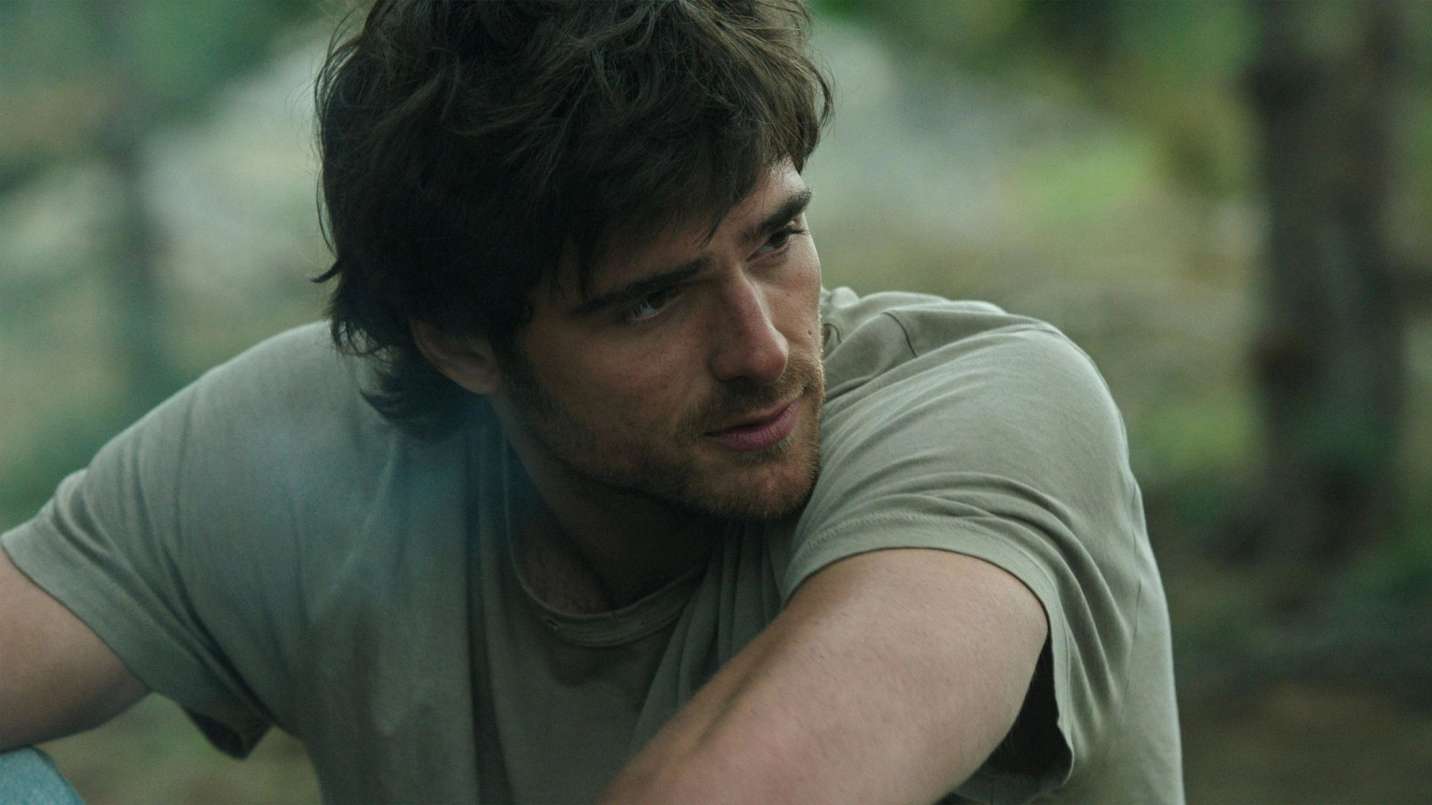 A close view of Hig in a light shirt looking to one side under soft lighting